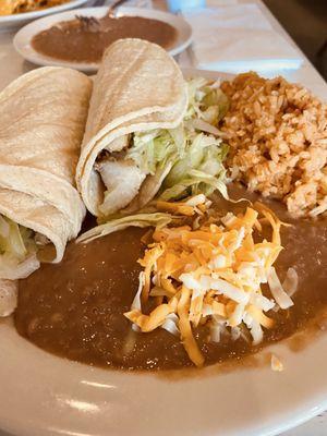 Grilled Pollack fish tacos with refried beans, rice, salad, and Mexican cheese