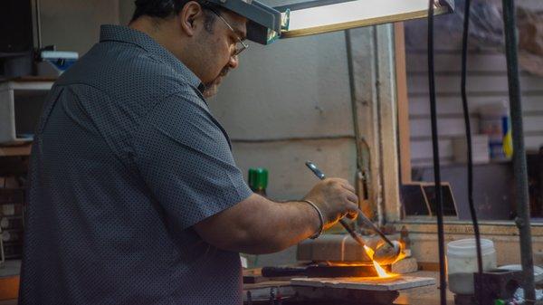 Jeweler pouring molten gold for a bar.