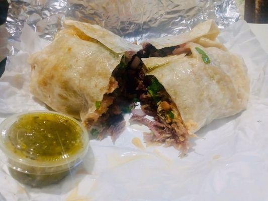 Carnitas Burrito Cut in half with green salsa on the side