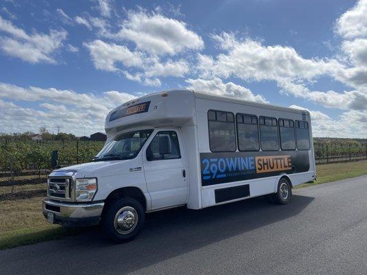 290 Wine Shuttle bus driving by vineyard.