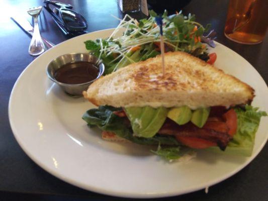 Bacon, lettuce, tomato and avocado sandwich with fresh greens on the side