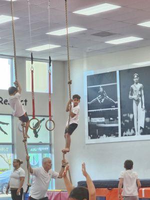 Coach Ruben holding the rope steady as my son and another boy try to climb to the top to ring the bell.