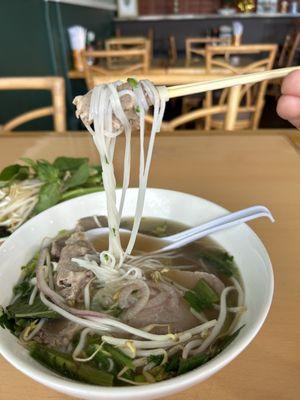 My house combination pho, using my chopsticks to pick up noodles and beef.