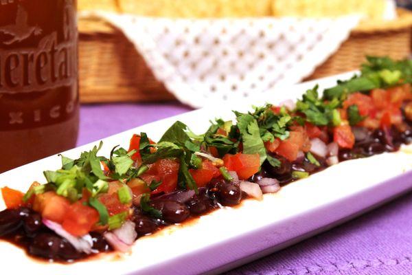 Dip de Frijol Negro - Black Bean Dip. Ccream cheese, layer of black beans and raspberry-chipotle sauce topped with tomatoes, onion, cilantro