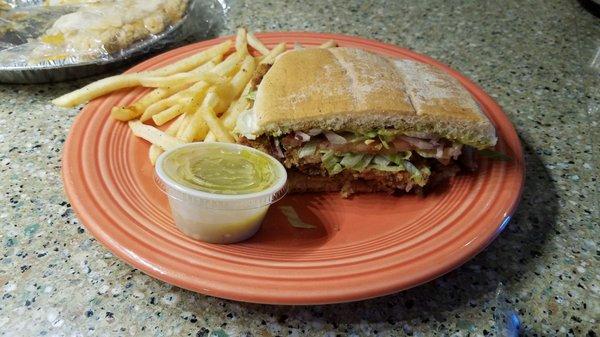 Half of torta filled with yummy fried pork, salad toppings,  and quacamole.