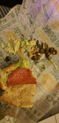 her sandwich which she has now torn apart. but u see the layer of pepperoni, lettuce and jalapeño lol.