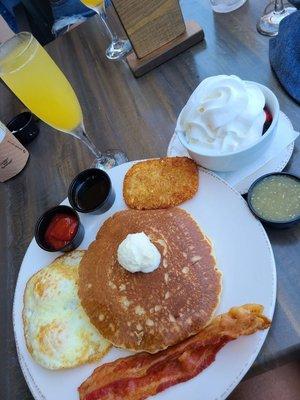 Pancakes, eggs, hashbrown and bacon combo. Side of fruit and mimosa.