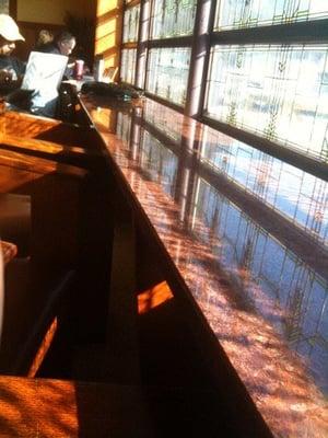 Counter with soft chairs in the front of the store, facingthe street through stained glass windows