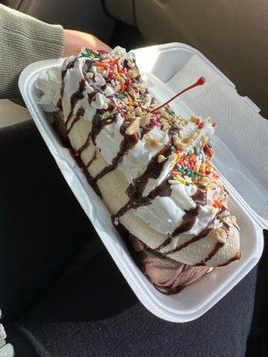 Main menu banana split with three scoops of ice cream cherry on top whip cream and sprinkles with chocolate syrup and nuts