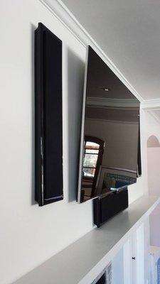 On wall ultra slim tilt-mount with slim home theater speakers.