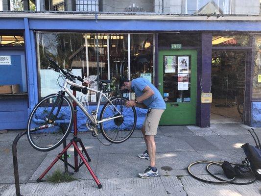 People fixing their own bikes in front of the shop