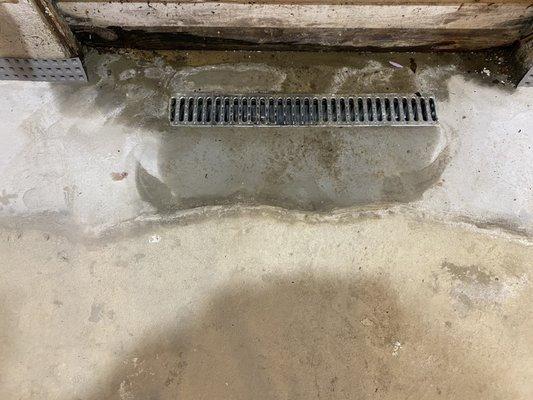 If the grate were longer or there was a trench created to make the water go into the grate this wouldn't be an issue