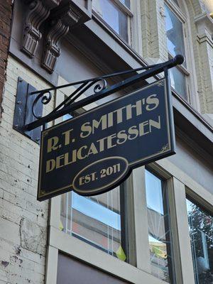 The outdoor restaurant's sign: black with golden letter fonts.