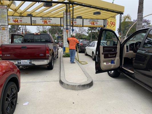 Our employee making sure your floor mats are thoroughly vacuumed at Five Points Carwash.