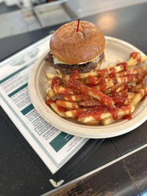 Blackened burger with fries. Ketchup added.