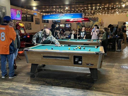 Customers playing pool between having pizza with friends