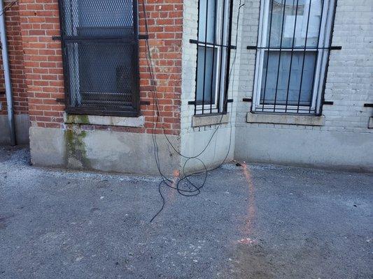 Wires hanging from the building on the outside.