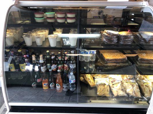 Refrigerator filled with desserts, sodas, chips and bread