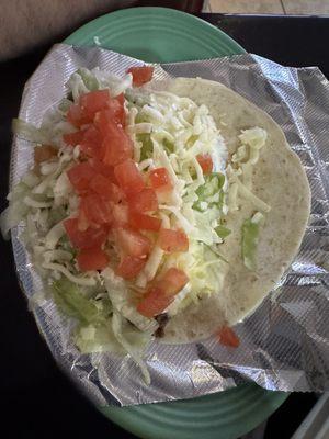 Ground beef taco with lettuce, cheese, tomatoes and sour cream