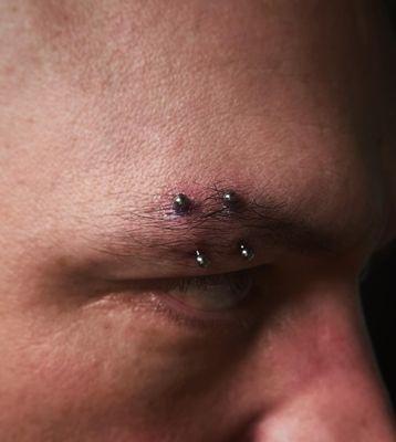 Double eyebrow piercing done with an implant grade titanium internally threaded curved barbell