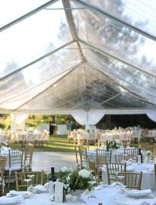 Clear top tent with lighting, dance floor, gold chiavari chairs, and a beautiful table setting!