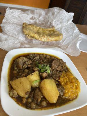 Goat curry with a small side of pumpkin with dal roti (small serving of rice not shown).