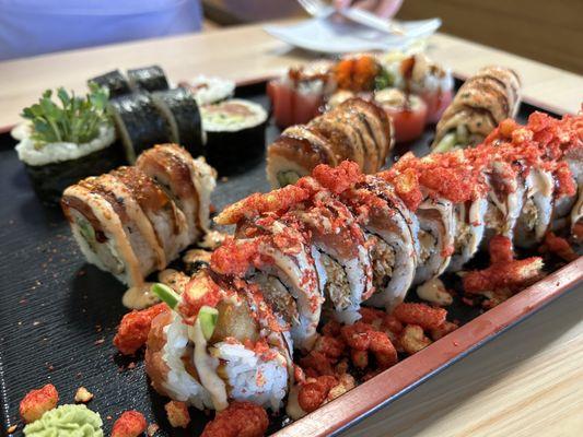 Assortment of sushi. Up front is Fuego Roll (hot Cheetos on top). Mean Jada (back left), Cherry Blossom (back right). Red Dragon (middle)