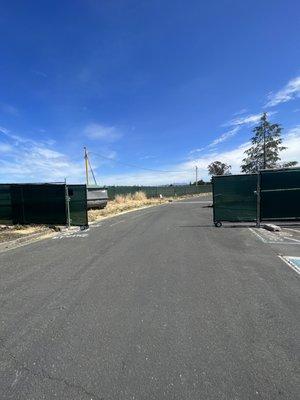 Temp fence installed inground with green privacy screen, includes roll back access gate.