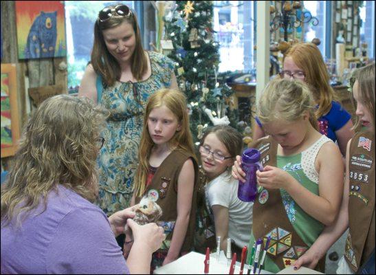 We are a family and kid friendly store. Here one of our artists demonstrates her craft to a Girl Scout troop.