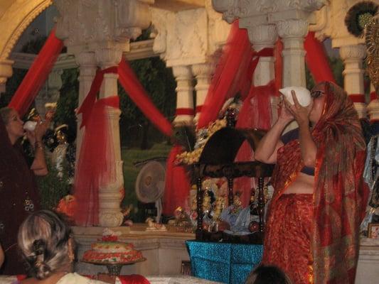 3 female pujaris blow a conch to herald the start of the evening worship.