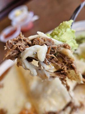 Close-up of a fork with a piece of the Shredded Beef Chimichanga and some guacamole.