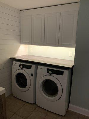 Laundry room transformation- Our expert craftsman framed the wall, added shiplap, painted, and installed cabinets and a countertop.