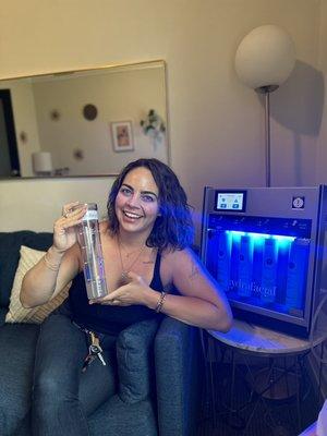 Happy and glowing client holding up what's in the gunky jar post Signature Glo Hydrafacial.