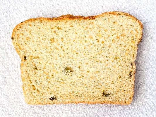 Slice of sourdough cheddar jalapeño showing slight cheddar top crust and pieces of jalapeño - just right!