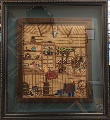 A shadow box holds the stitched and framed family treasure under glass.