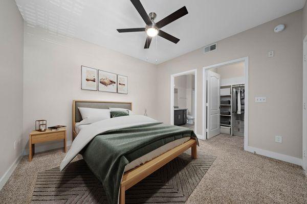 The Met furnished bedroom model unit, with ceiling fan, carpet floors, wall art