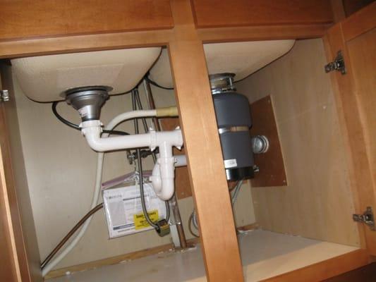 Kitchen sink drain piping configured for maximum under sink cabinet storage.