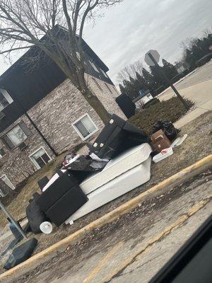 Someone's old furniture just thrown on the side of the entrance to the buildings.