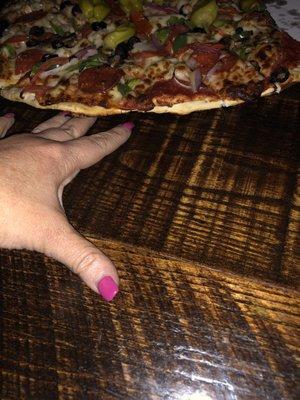 The pizza sitting in the table with my hand underneath it- gross!