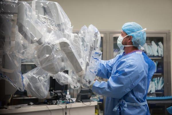 Healthcare worker preparing the da Vinci robot for surgery.