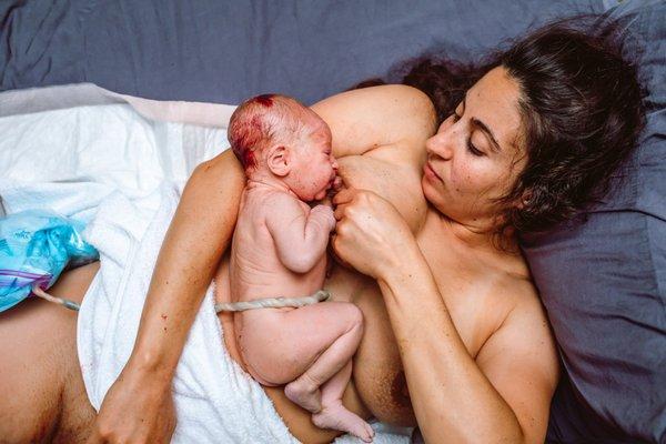 VBAC mama holds and does skin to skin and the first breastfeeding following her home birth vbac with midwife in Boca Raton