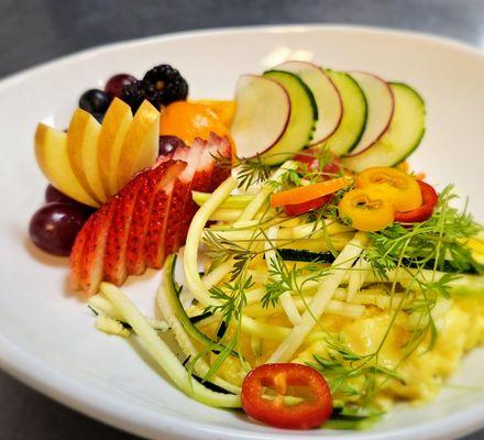 Garden Brie Scramble with soft scrambled eggs, fresh vegetables, fruit, and microgreens