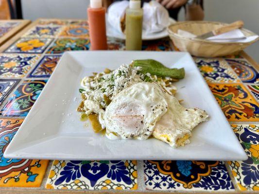 Salsa Verde Chilaquiles with Eggs - lightly fried corn tortillas, topped with spicy salsa verde, cotija cheese, and eggs