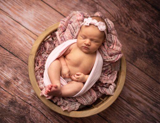 baby girl in basket with pink wrap