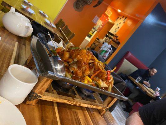 Fish skewers with vegetables in sauce on hot plate