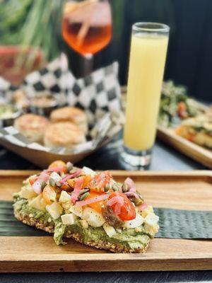 Avocado toast with chopped egg, tomato, onion, and pepitas