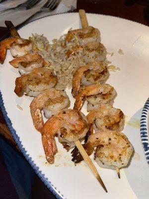 Grilled shrimp skewer over rice