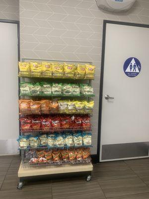 Assorted chips/snacks next to a gender neutral restroom.