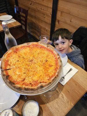 Young child devours red pie with mozzarella