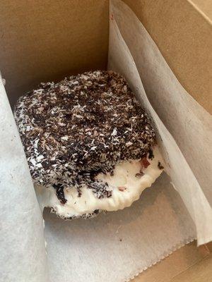 Lamington-vanilla sponge cake dipped in chocolate icing and coconut, filled with raspberry jam & vegan whipped cream